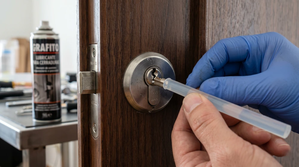 Primer plano técnico de una barra de silicona aplicada sobre un bombín para sacar una llave partida de una cerradura de puerta.